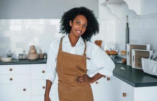 Aan de keuken. jong Afrikaanse Amerikaans vrouw met gekruld haar- binnenshuis Bij huis foto