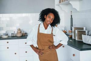 Aan de keuken. jong Afrikaanse Amerikaans vrouw met gekruld haar- binnenshuis Bij huis foto