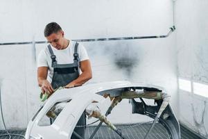 werken met auto kap. Kaukasisch auto- klusjesman in uniform in garage foto