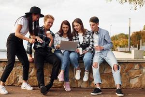 gebruik makend van laptop. groep van jong vrolijk vrienden dat is buitenshuis hebben pret samen foto