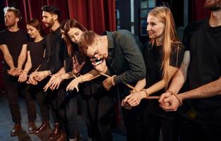 met touw in handen. groep van acteurs in donker gekleurde kleren Aan repetitie in de theater foto