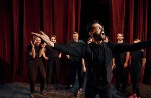 uitdrukbaar vent beoefenen zijn rol. groep van acteurs in donker gekleurde kleren Aan repetitie in de theater foto