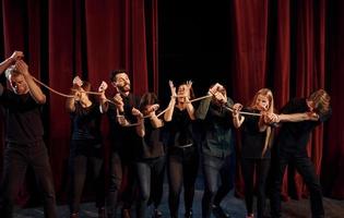 knoop in de handen. groep van acteurs in donker gekleurde kleren Aan repetitie in de theater foto