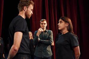 twee mensen praten. groep van acteurs in donker gekleurde kleren Aan repetitie in de theater foto