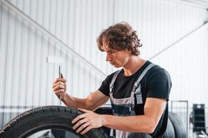 werken met band. volwassen Mens in grijs gekleurde uniform is in de auto- salon foto