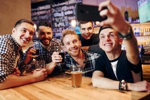 Mens duurt selfie door telefoon. groep van mensen samen binnenshuis in de kroeg hebben pret Bij weekend tijd foto