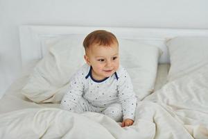 schattig weinig jongen is Aan de bed. interieur en ontwerp van mooi modern slaapkamer Bij dag foto