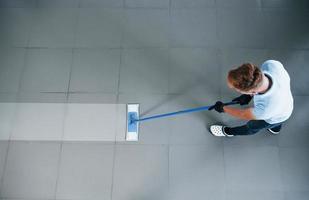 top visie van Mens in blauw overhemd en beschermend handschoenen dat toepassingen vacuüm schoonmaakster foto