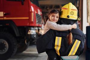 gelukkig weinig meisje is met vrouw brandweerman in beschermend uniform foto