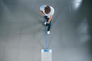 top visie van Mens in blauw overhemd en beschermend handschoenen dat toepassingen vacuüm schoonmaakster foto