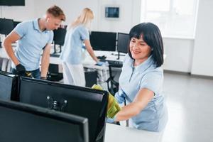 reinigt monitor. groep van arbeiders schoon modern kantoor samen Bij dag foto