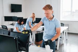 reinigt monitor. groep van arbeiders schoon modern kantoor samen Bij dag foto