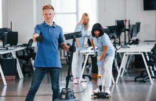 vent met vacuüm schoner. groep van arbeiders schoon modern kantoor samen Bij dag foto