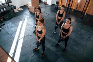 hijs- van zwaar gewichten. groep van jong sportief mensen hebben crossfit dag binnenshuis in Sportschool foto