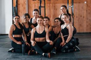 zittend Aan vloer. groep van jong sportief mensen hebben crossfit dag binnenshuis in Sportschool foto