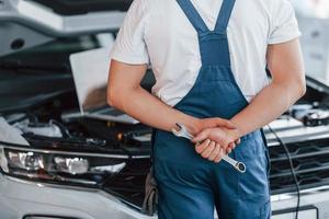 toepassingen laptop. jong Mens in wit overhemd en blauw uniform reparaties auto- foto