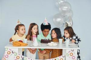 zit door de tafel. kinderen Aan vieren verjaardag partij binnenshuis hebben pret samen foto