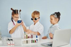 staand door de tafel met test buizen. kinderen in wit jassen Toneelstukken een wetenschappers in laboratorium door gebruik makend van uitrusting foto