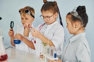 kinderen in wit jassen Toneelstukken een wetenschappers in laboratorium door gebruik makend van uitrusting foto