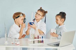 staand door de tafel met test buizen. kinderen in wit jassen Toneelstukken een wetenschappers in laboratorium door gebruik makend van uitrusting foto