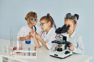 kinderen in wit jassen Toneelstukken een wetenschappers in laboratorium door gebruik makend van uitrusting foto