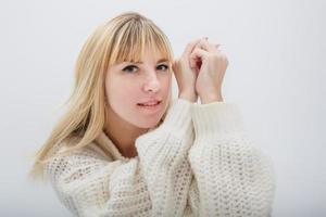 dichtbij omhoog portret van blond meisje model- in wit wol trui Aan wit achtergrond in studio foto