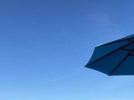 blauw strand paraplu Aan zomer blauw lucht achtergrond foto