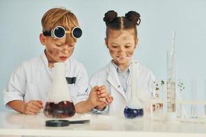 jongen werken met vloeistof in test buizen. kinderen in wit jassen Toneelstukken een wetenschappers in laboratorium door gebruik makend van uitrusting foto