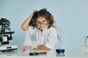 niet succesvol experiment. weinig meisje in jas spelen een wetenschapper in laboratorium door gebruik makend van uitrusting foto