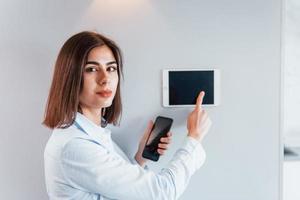 toepassingen tablet dat is gemonteerd in de muur. jong vrouw is binnenshuis in slim huis kamer Bij dag foto