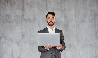 toepassingen laptop. jong elegant zakenman in pak binnenshuis. opvatting van succes foto