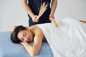 vent toepassingen speciaal stokken. jong vrouw is aan het liegen naar beneden wanneer Mens aan het doen massage van haar lichaam Bij spa foto