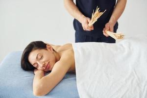 speciaal apparatuur. jong vrouw is aan het liegen naar beneden wanneer Mens aan het doen massage van haar lichaam Bij spa foto