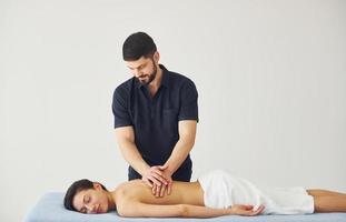 jong vrouw is aan het liegen naar beneden wanneer Mens aan het doen massage van haar terug Bij spa foto