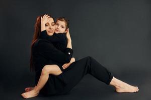 moeder en dochter is samen in de studio tegen zwart achtergrond foto