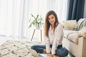 mooi jong vrouw in jeans en wit overhemd is Bij huis foto