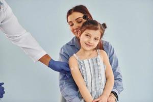 moeder met haar weinig dochter is in de ziekenhuis met Afrikaanse Amerikaans dokter foto