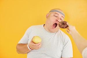 appel of koekje. grappig te zwaar Mens in sportief hoofd stropdas is tegen geel achtergrond foto