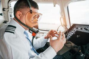 in zuurstof masker. piloot Aan de werk in de passagier vliegtuig. voorbereidingen treffen voor uittrekken foto