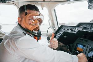 in zuurstof masker. piloot Aan de werk in de passagier vliegtuig. voorbereidingen treffen voor uittrekken foto