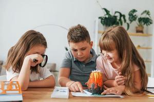 gebouw vulkaan van plasticine. kinderen hebben pret in de huiselijk kamer Bij dag samen foto