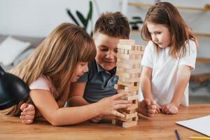 door elkaar gooien toren spel. kinderen hebben pret in de huiselijk kamer Bij dag samen foto