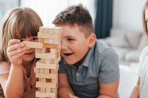 door elkaar gooien toren spel. kinderen hebben pret in de huiselijk kamer Bij dag samen foto