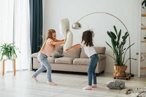 hoofdkussen gevecht. kinderen hebben pret in de huiselijk kamer Bij dag samen foto