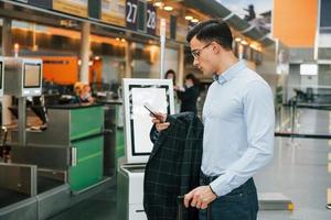 Holding telefoon. jong zakenman in formeel kleren is in de luchthaven Bij dag foto