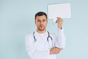 in dokter uniform. Mens staand in de studio met leeg tekens voor de tekst foto