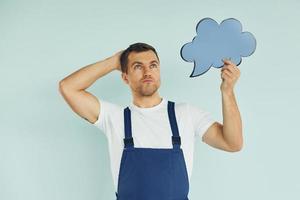 in blauw uniform. Mens staand in de studio met leeg tekens voor de tekst foto