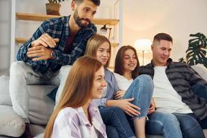 zittend Aan de bank. groep van vrienden hebben partij binnenshuis samen foto