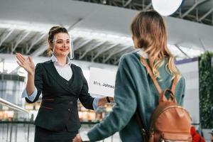 vrouw met bord met tekst. jong vrouw toerist is in de luchthaven Bij dag foto