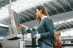 gebruik makend van terminal. jong vrouw toerist is in de luchthaven Bij dag foto